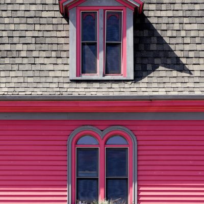 A vertical shot of a beautiful wooden pink and grey house captured at day time